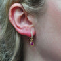Gold Huggie Hoop Earrings with Diamonds & Ruby Charms on white female model | Rebecca Myers Collection