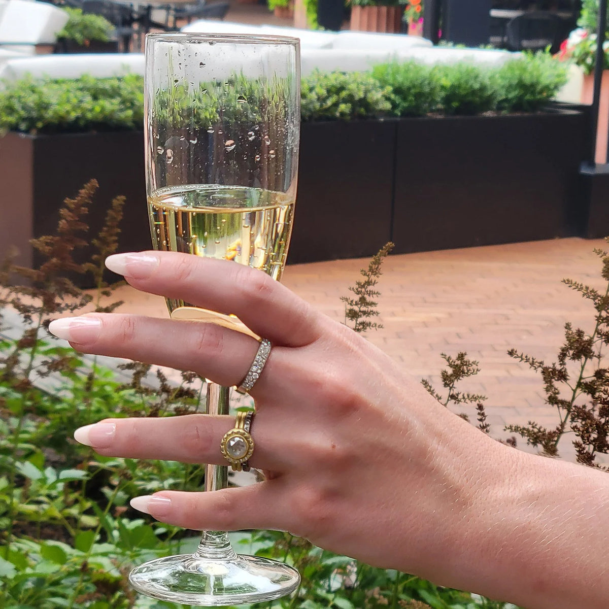 Natural Diamond Halo Rings on white female model holding glass of champagne | Rebecca Myers Collection