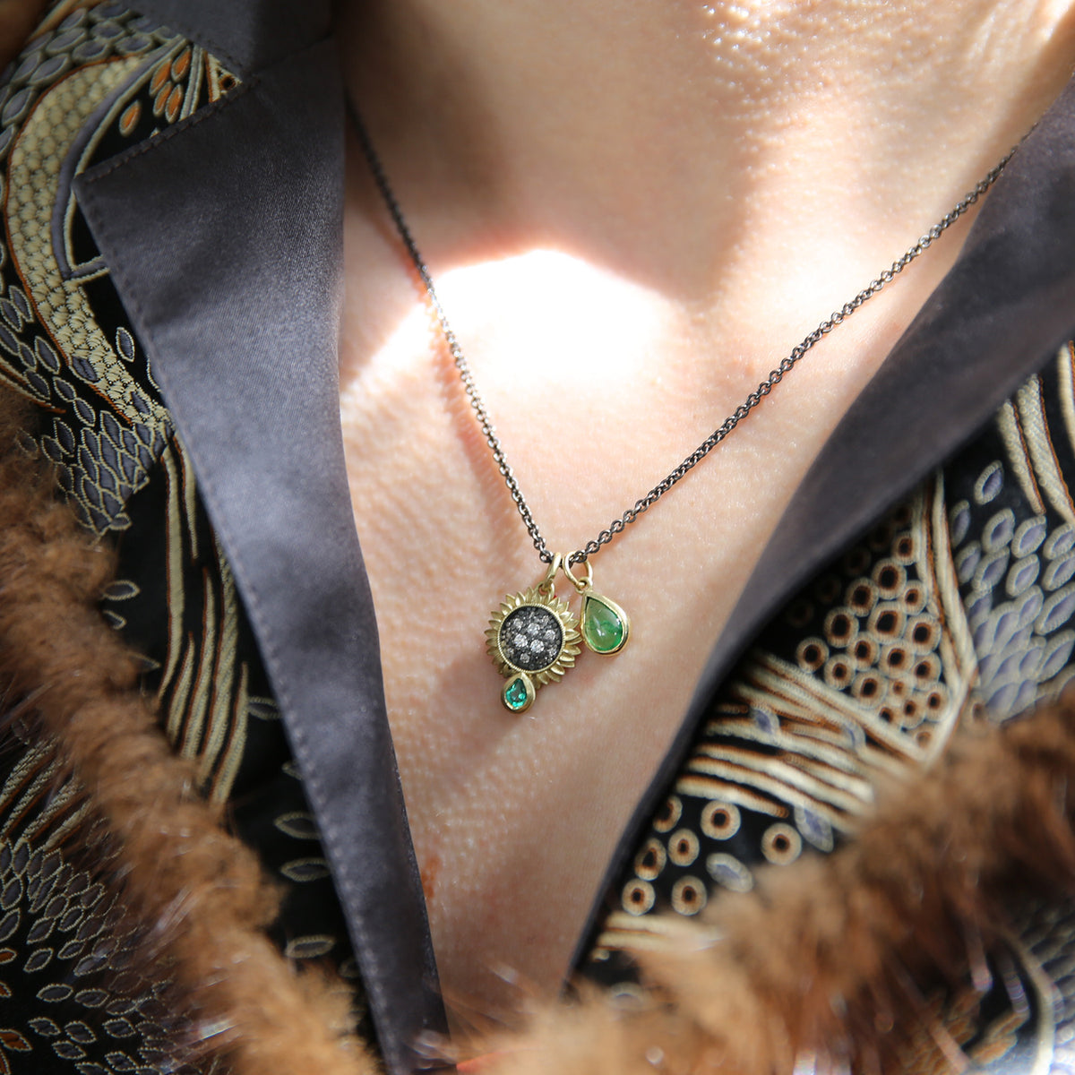 Small Pave Diamond Sunflower Charm with Emerald Teardrop on Oxidized Silver Cable Chain + Tsavorite Teardrop Charm on white female model in brocade jacket | Rebecca Myers Collection
